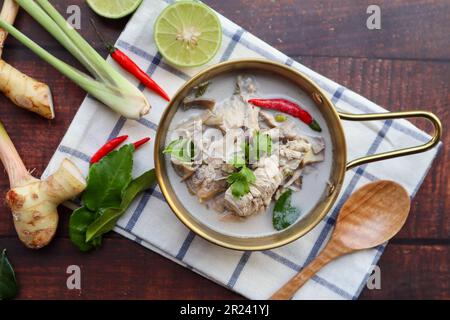 Soupe thaïlandaise de poulet à la noix de coco avec quelques ingrédients sur une table en bois à la vue du dessus - cuisine thaïlandaise appelée Tom Kha Gai Banque D'Images