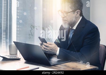 Composition graphique d'un homme mûr, vers 50, assis à un bureau vérifiant les données financières sur un téléphone et une tablette, superposée avec des tableaux financiers et Banque D'Images