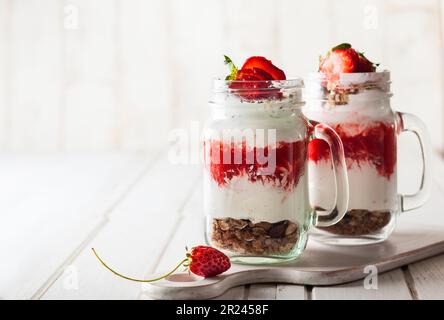 Petit déjeuner sain dans un pot Mason avec yaourt, purée de fraises et muesli Banque D'Images