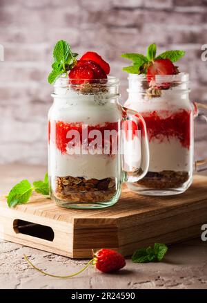 Petit déjeuner sain dans un pot Mason avec yaourt, purée de fraises et muesli Banque D'Images