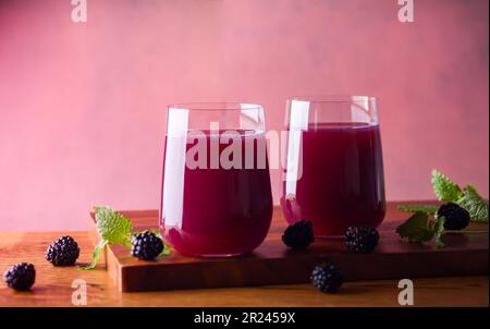 Jus de mûre frais dans des verres avec menthe et baies fraîches sur la table en bois. Banque D'Images