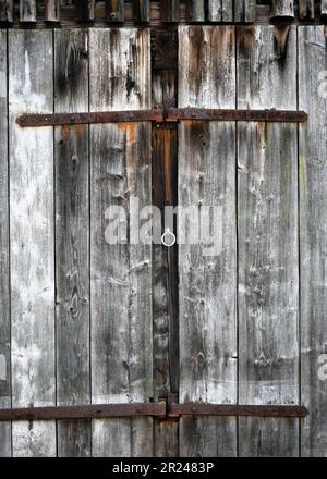 Ancienne ancienne porte de grange en bois patiné avec pièces en métal forgé. Style rustique. Copier l'espace. Banque D'Images
