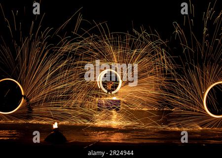 la nuit, sur une plage de sable, vous pouvez tirer sur des jongleurs avec des étincelles Banque D'Images