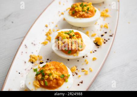 Œufs farcis à la crème de thon et de tomate. Recette traditionnelle de tapa espagnole. Banque D'Images