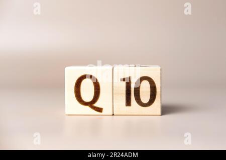 Le mot Q10 sur des cubes en bois sur un fond beige neutre studio. Copier l'espace. Écrit. Les mots de texte ont leur importance. Coenzyme, CoQ10 suppléments pour la santé humaine Banque D'Images