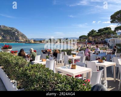 Italie, personnes sur une terrasse au bord de la mer bleue en été en Sicile. Vue sur la mer bleue italienne depuis une terrasse avec tables basses Banque D'Images