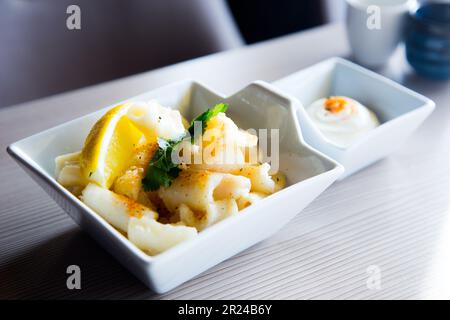 Rajas al ajillo. Rabique cuit à l'ail. Tapa de jambe de calmar servi avec du citron. Tapa traditionnel espagnol. Banque D'Images