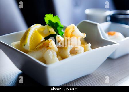 Rajas al ajillo. Rabique cuit à l'ail. Tapa de jambe de calmar servi avec du citron. Tapa traditionnel espagnol. Banque D'Images