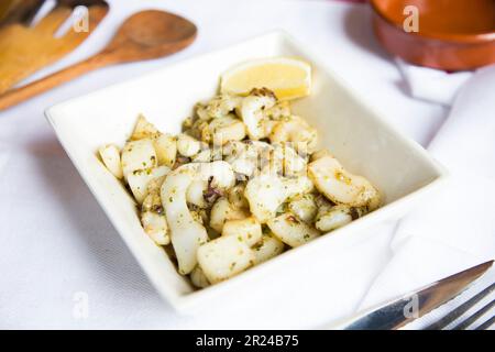 Rajas al ajillo. Rabique cuit à l'ail. Tapa de jambe de calmar servi avec du citron. Tapa traditionnel espagnol. Banque D'Images