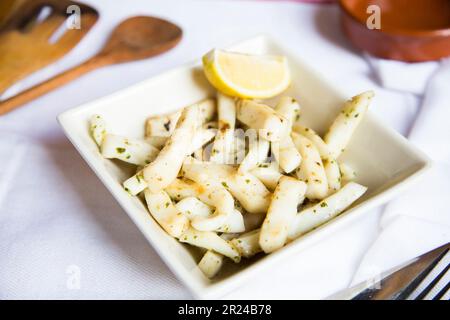 Rajas al ajillo. Rabique cuit à l'ail. Tapa de jambe de calmar servi avec du citron. Tapa traditionnel espagnol. Banque D'Images