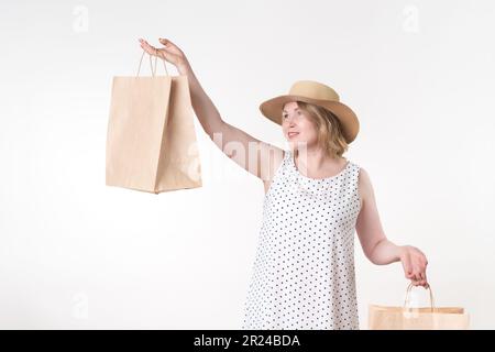 Une cabas tient des sacs de shopping en papier dans les mains. Une main avec le sac est levée, la femme la regarde Banque D'Images