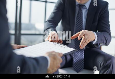 Deux hommes d'affaires sont assis sur des chaises dans le bureau pendant la conclusion d'un accord. Banque D'Images