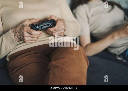 Photo rognée de deux femmes jouant à des jeux vidéo à la maison, assis sur un canapé et se appréciant, ayant un grand week-end en compagnie belle à l'intérieur. Couple Banque D'Images