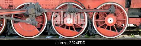 Grandes roues rouges, volants, bielles et autres machines d'une ancienne locomotive à vapeur. Banque D'Images