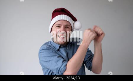 Le joyeux jeune homme européen dans un chapeau du nouvel an danse joyeusement à la fête. Prise de vue en studio Banque D'Images