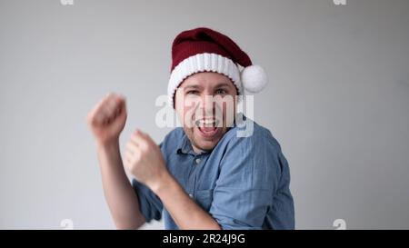 Le joyeux jeune homme européen dans un chapeau du nouvel an danse joyeusement à la fête. Prise de vue en studio Banque D'Images