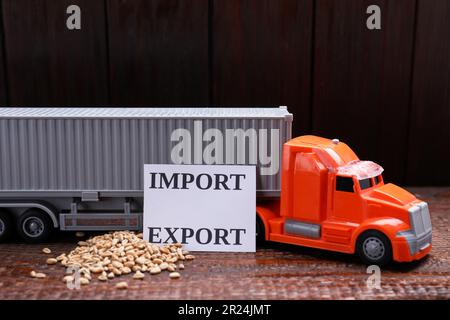 Carte avec mots Importer et exporter près d'un camion jouet et de grains de blé sur une table en bois Banque D'Images