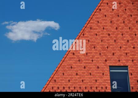 carrelage moderne en argile brun rouge toit résidentiel incliné. protection métallique contre la neige et la glace. ciel bleu et nuages blancs. concept de construction. matériaux de toiture modernes Banque D'Images