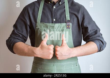 Un homme dans un tablier de cuisine. Le chef travaille dans la cuisine. Cuire dans des vêtements de protection uniformes. Travail dans le service alimentaire. Cuisine professionnelle. Tablier en tissu vert Banque D'Images