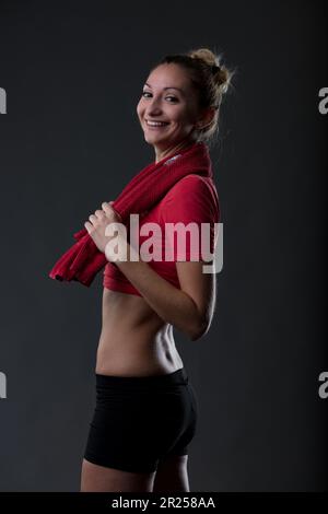 Portrait d'une fille attrayante en tenue de gym, fière de son estomac plat et des fesses fermes. Porter un haut rouge et un pantalon noir serré. « Si j'apprécie un Banque D'Images