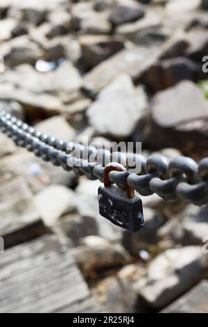 Cadenas rouillé accroché d'un maillon de chaîne descendant jusqu'au quai de la Nouvelle-Orléans, LA. Symbole parfait pour l'amour et capture la décomposition naturelle du temps. Banque D'Images