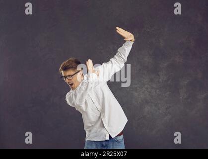 Peur jeune homme caucasien se fermant en sentant la peur debout sur un fond gris. Banque D'Images