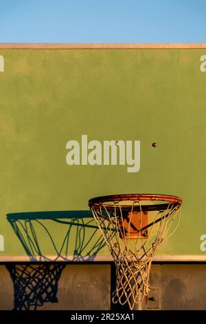 Vue rapprochée d'un panier de basket-ball sur un coucher de soleil contre le ciel bleu. Banque D'Images