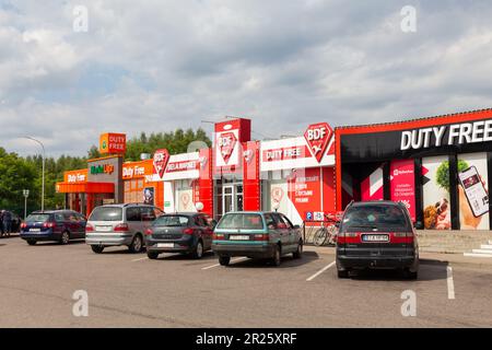 Bruzgi, Bélarus - 11 août 2019: Les voitures franchissant la frontière sont garées à proximité de magasins en zone hors taxes au point de contrôle de Bruzgi Banque D'Images