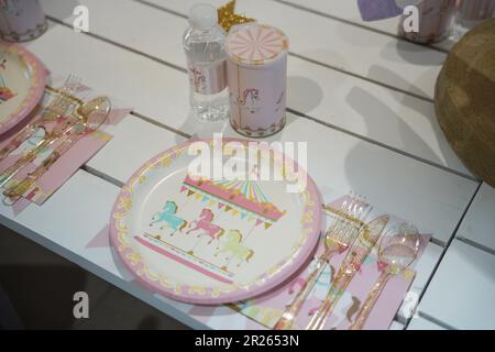 Table de fête sur le thème du carnaval ou du carrousel pour enfants avec assiettes en plastique et bonbons. Décoration festive pour une fête d'anniversaire de petite fille avec déjeuner ta Banque D'Images