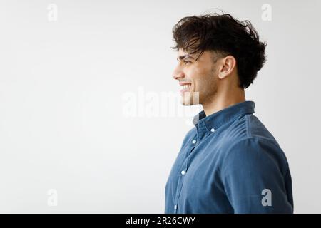 Photo de profil de l'homme du Moyen-Orient souriant contre le mur blanc Banque D'Images