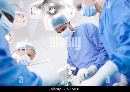 Notre équipe travaille ensemble pour sauver des vies. Vue basse des médecins effectuant une chirurgie dans un bloc opératoire. Banque D'Images
