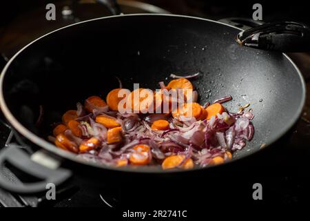 Les oignons et les carottes sont frits dans une poêle à frire profonde. Préparation de la cuisson. Banque D'Images