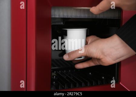 Femme prenant une tasse en papier avec du café du distributeur automatique, gros plan Banque D'Images