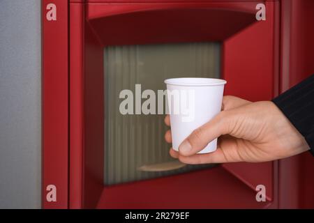 Femme prenant une tasse en papier avec du café du distributeur automatique, gros plan Banque D'Images