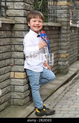 Un garçon avec une bouteille d'eau dans sa main. Un enfant avec une bouteille d'eau dans sa main. Banque D'Images