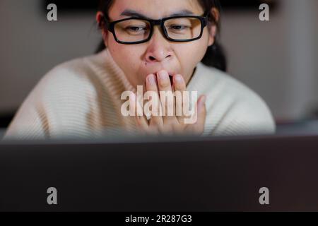 Femme bâilleuse et endormie travaillant sur un ordinateur portable au bureau à la maison. Femme d'affaires fatiguée portant des lunettes en utilisant un ordinateur portable assis au bureau et faisant des recherches Banque D'Images