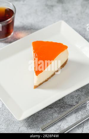 Cheesecake à la citrouille sur une assiette en porcelaine avec thé sur une table en pierre Banque D'Images