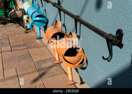 Cinq arrosoirs en métal de couleur pour les enfants accrochés au mur Banque D'Images