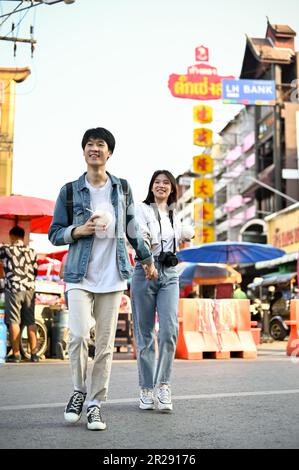 Chiang Mai, Thaïlande - 17 mai 2023: Charmant jeune couple de touristes asiatiques se tenant les mains en traversant la rue, aime visiter la Chinato de Chiang Mai Banque D'Images