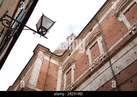 Petite église fortifiée en brique et pierre et vue sur la rue depuis la ville historique italienne de Sienne en Toscane. Banque D'Images