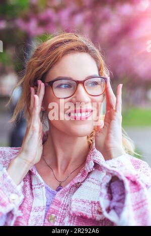 Une femme de race blanche positive a mis des lunettes pour voir clairement à l'extérieur Banque D'Images