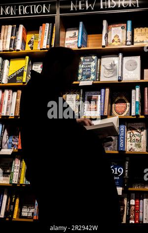 La silhouette d'une personne qui navigue parmi les livres dans une boutique de livres Waterstones en Angleterre au Royaume-Uni. Banque D'Images