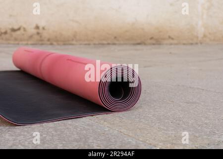 vue rapprochée du tapis de fitness rose et noir sur le trottoir extérieur, espace de copie, style de vie urbain Banque D'Images