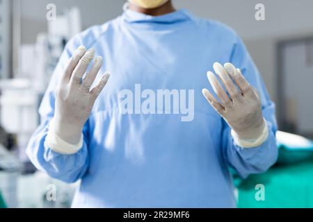Section médiane du chirurgien portant une blouse chirurgicale et des gants dans le bloc opératoire Banque D'Images