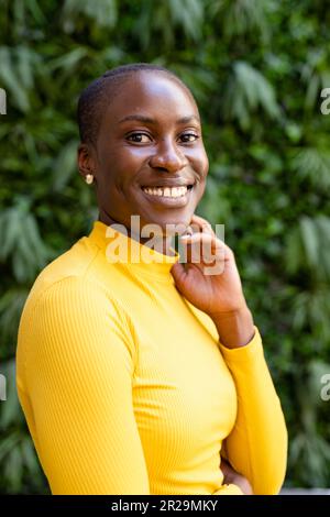 Portrait d'une femme d'affaires afro-américaine souriante aux cheveux courts qui posaient contre les plantes Banque D'Images