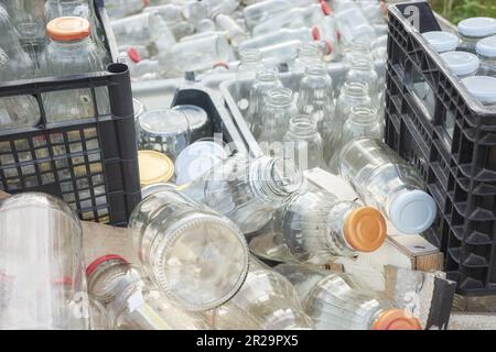 Divers types de bouteilles en verre vides stockés dans des récipients pour recyclage, concentration sélective. Banque D'Images