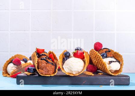 Diverses crèmes glacées au taco sucré. Coquilles de tacos à gaufrer avec glace au chocolat et à la vanille avec différents fruits, baies, garnitures Banque D'Images