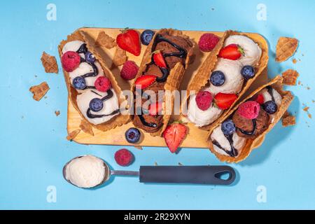 Diverses crèmes glacées au taco sucré. Coquilles de tacos à gaufrer avec glace au chocolat et à la vanille avec différents fruits, baies, garnitures Banque D'Images