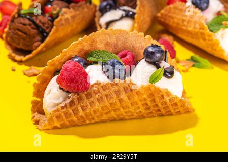Diverses crèmes glacées au taco sucré. Coquilles de tacos à gaufrer avec glace au chocolat et à la vanille avec différents fruits, baies, garnitures Banque D'Images
