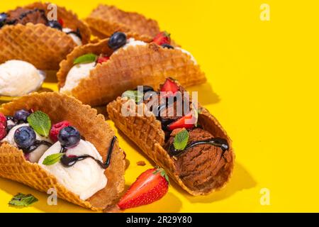 Diverses crèmes glacées au taco sucré. Coquilles de tacos à gaufrer avec glace au chocolat et à la vanille avec différents fruits, baies, garnitures Banque D'Images